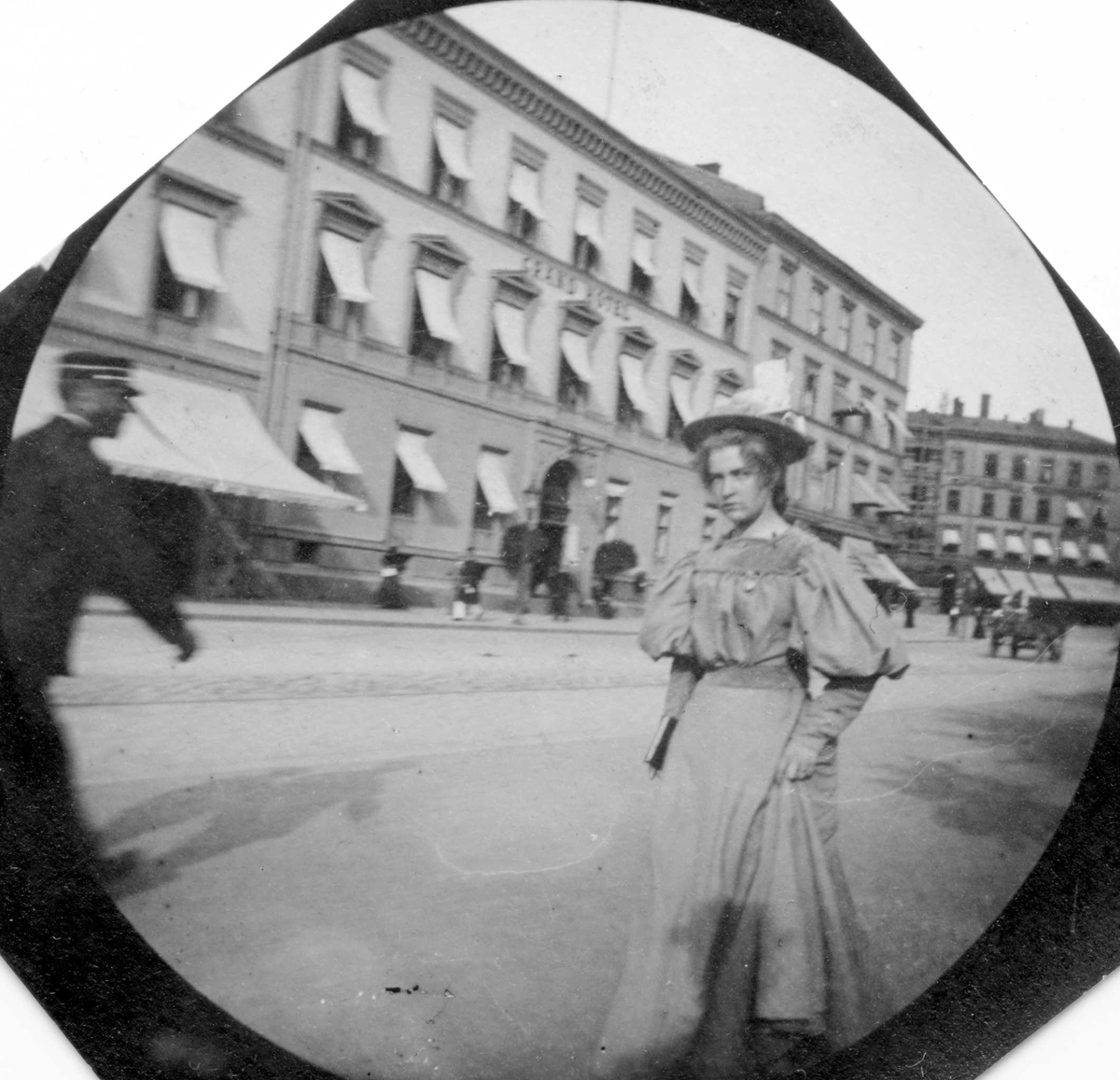 Fredrik Carl Mülertz Størmer, Frk. Herlofsen spaserer langs Karl Johans gate, Oslo, med Grand Hotel på den andre siden.