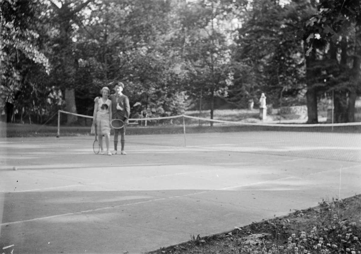 Okänd,, Two young people, girl and boy standing on tennis court with tennis racket in hand, likely in Sweden