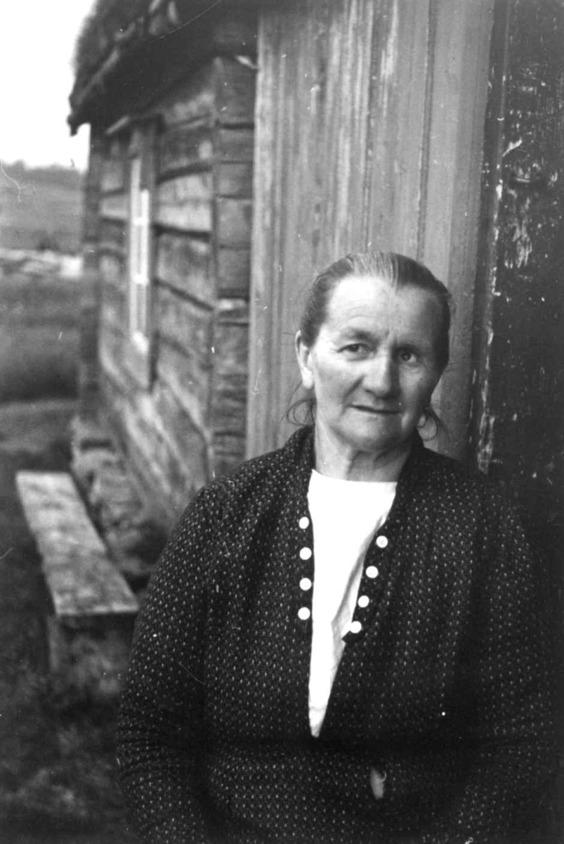 Anna Grostøl, Portrett av en ukjent kvinne utenfor et hus. Brekken eller Røros, Sør-Trøndelag 1938.
