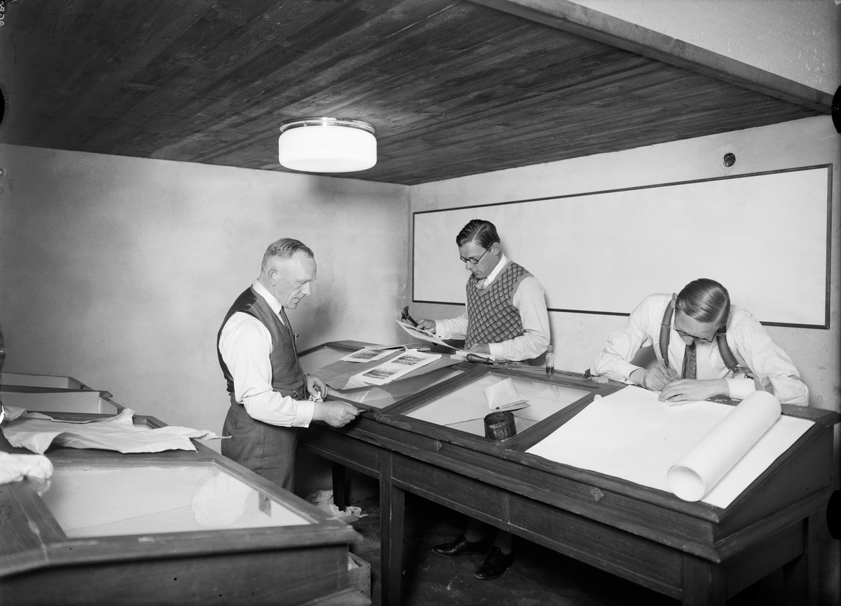 Paul Sandberg, Amanuens Nils Sundquist och hans medhjälpare lägger fynd från utgrävningen av Rudbeckstomten i montrar, Upsala Fabriks- och handtverksförenings utställningslokal i kvarteret Näktergalen, Stora Torget