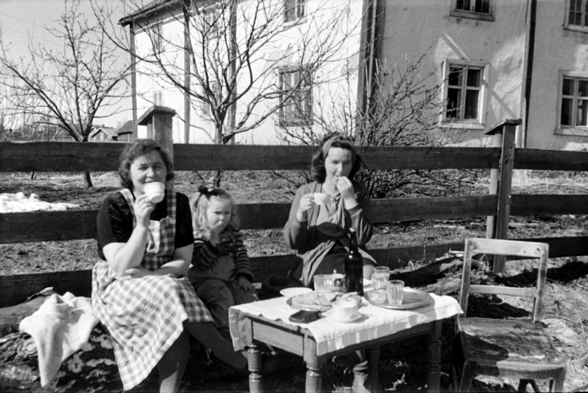 Adolf Skjegstad, KAFFEPAUSE UTE I VÅRSOLA. Ukjent våningshus i bakgrunnen, rappet.