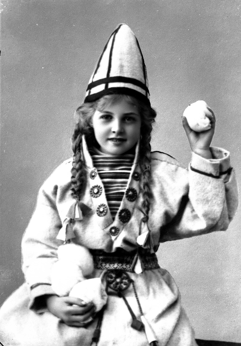 Solveig Lund, Pike i sameliknende drakt med kofte, lue og belte. I hendene holder hun jukse snøballer.