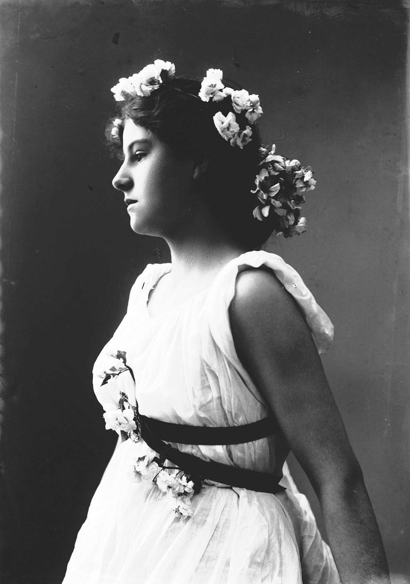 Solveig Lund, Studioportrett av kvinne i drakt med blomster i håret.