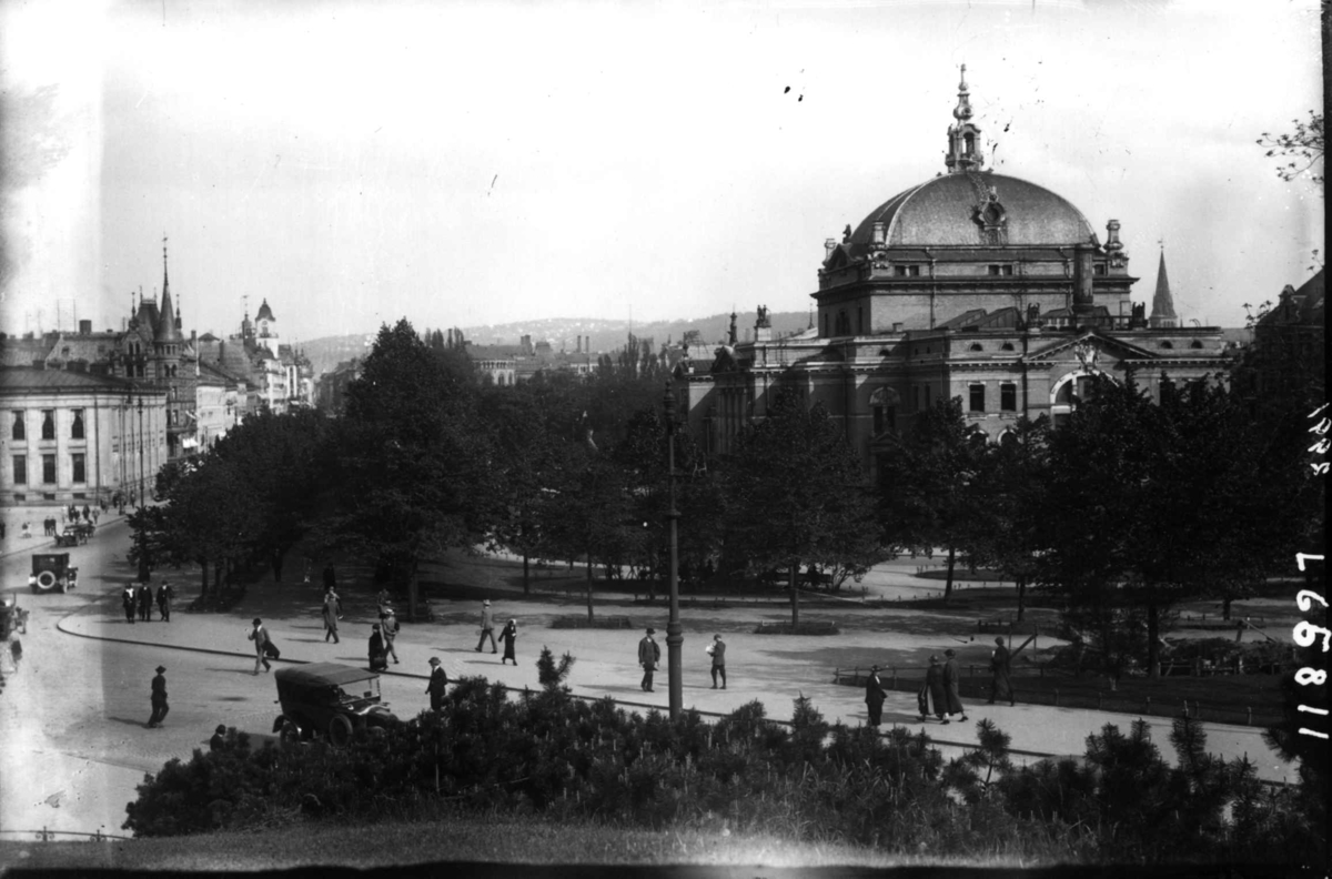 Hermann Christian Neupert, Oslo, Nationaltheateret sett fra Slottsparken. Fotgjengere. Biler. Trær i bakgrunnen.