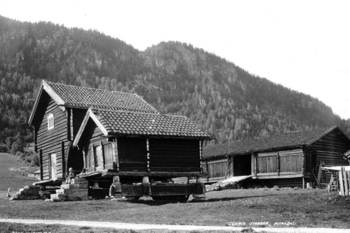Hermann Christian Neupert, Tveiten, Nore og Uvdal. 1930. Fra gårdstun med uthus. Låve, loft og stabbur. Fjell i bakgrunnen.