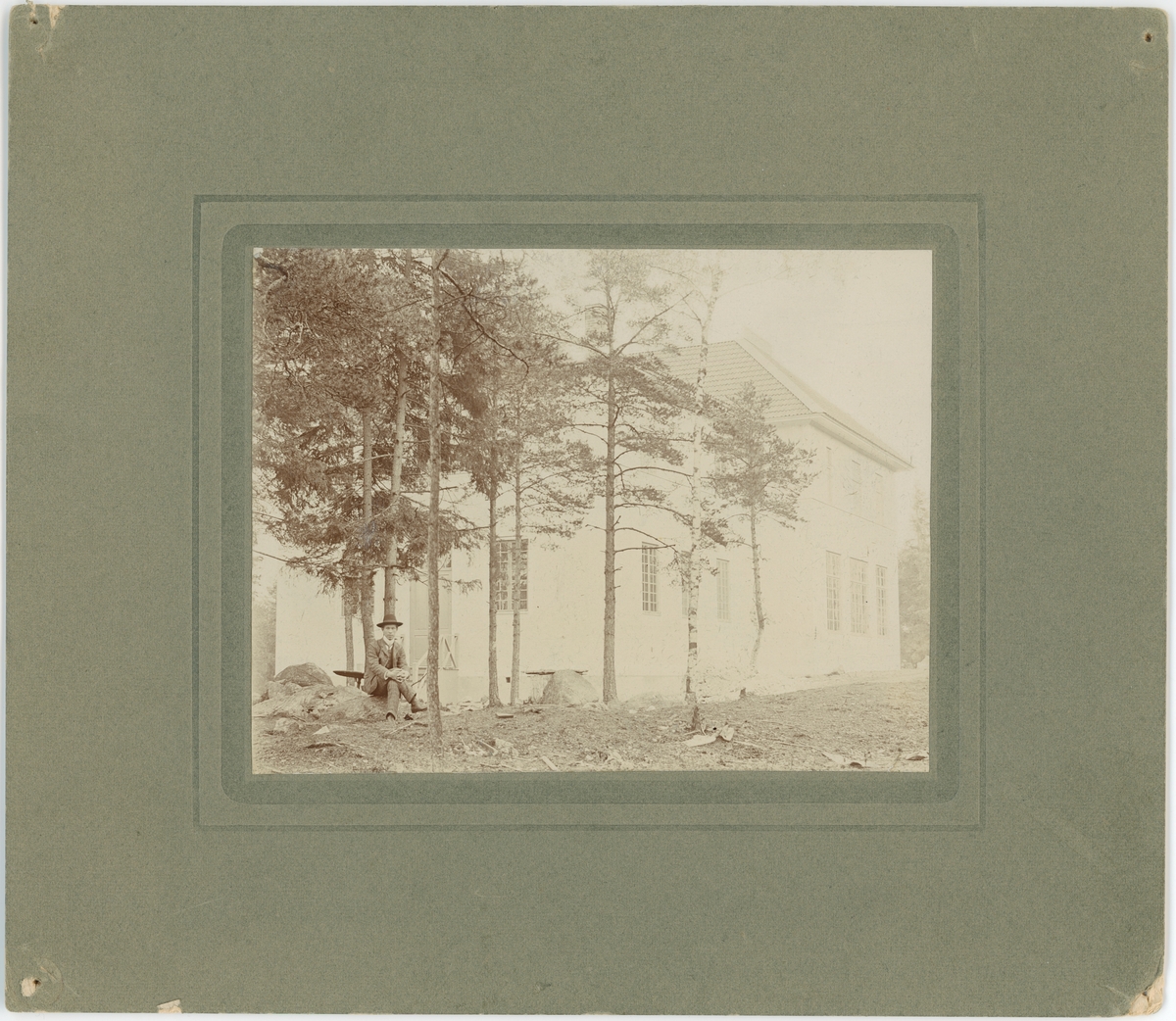 Okänd,, Man sitting on a stone with a large building behind him, Uppsala