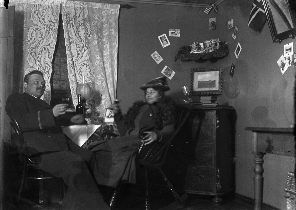 Johannes Larsen Alhaug, Interiør, stue. Johannes og Johanne (?) Alhaug sitter ved et bord og drikker.