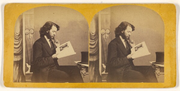 Unknown, [Bearded man with long hair looking at a photograph]