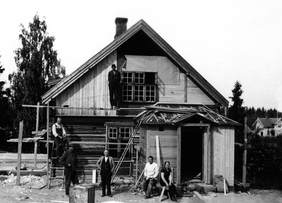 Anno Domkirkeodden, GRUPPE 6, SNEKKERE I STILAS, HUS UNDER OPPFØRING PÅ PAUL HVALS EIENDOM LUNDE I GATA I VALLSET PÅ 1930-TALLET. PERSONENE PÅ BILDET ER: SITTENDE I STIGEN: ALBERT RØSTAD. OPPE PÅ STILLASET: EMIL OTTINSEN. PÅ BAKKEN FRA V. : ARNE MYGLAND, PAUL HVAL, F. 1888 SIGURD HVAL F. 1890 OG BORHILD HVAL MYGLAND F…