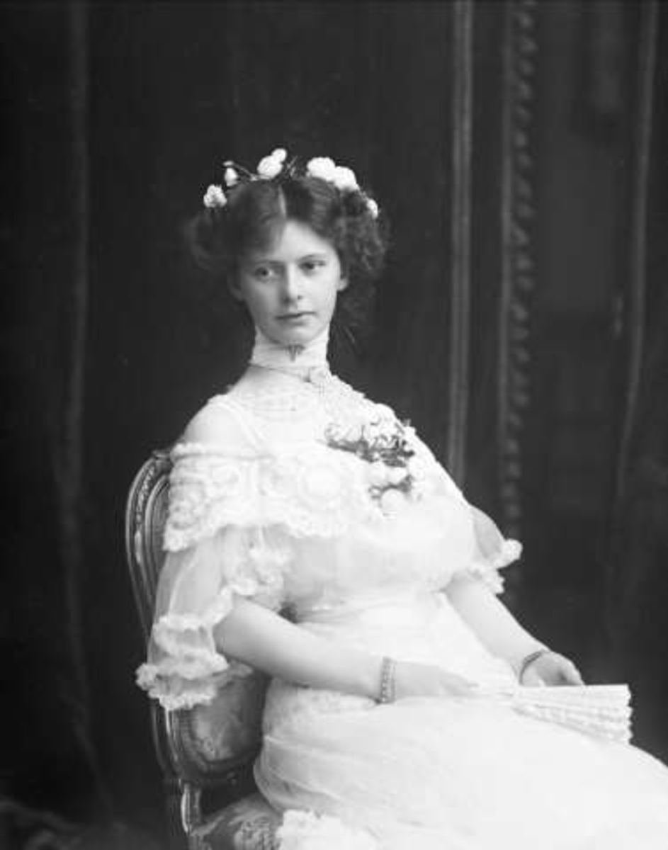 Gustav Borgen, Portrett, kvinne i hvit kjole, med blomst på brystet og håndvifte. Frøken C. Larsen, overrettssakfører Larsens datter(?)