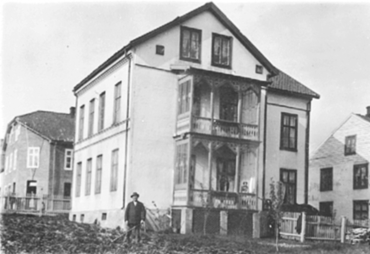 Anno Domkirkeodden, EKSTERIØR SKAPPELSGATE 4 I HAMAR, FOSSUMSGÅRDEN, FOSSUMGÅRDEN FRA HAGESIDEN, MANN I FORGRUNNEN HOLDER PÅ MED HAGEARBEID. VERANDA.