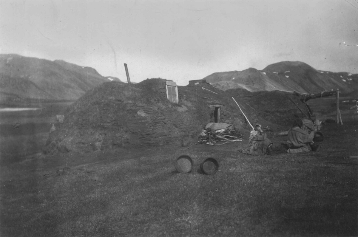 Konrad Nielsen, Guttorms gamme, opprinnelig fellesgamme omgjort til fjøsgamme med tilbygget boliggamme, utenfor sitter to personer. Gulgofjord, Berlevåg kommune.