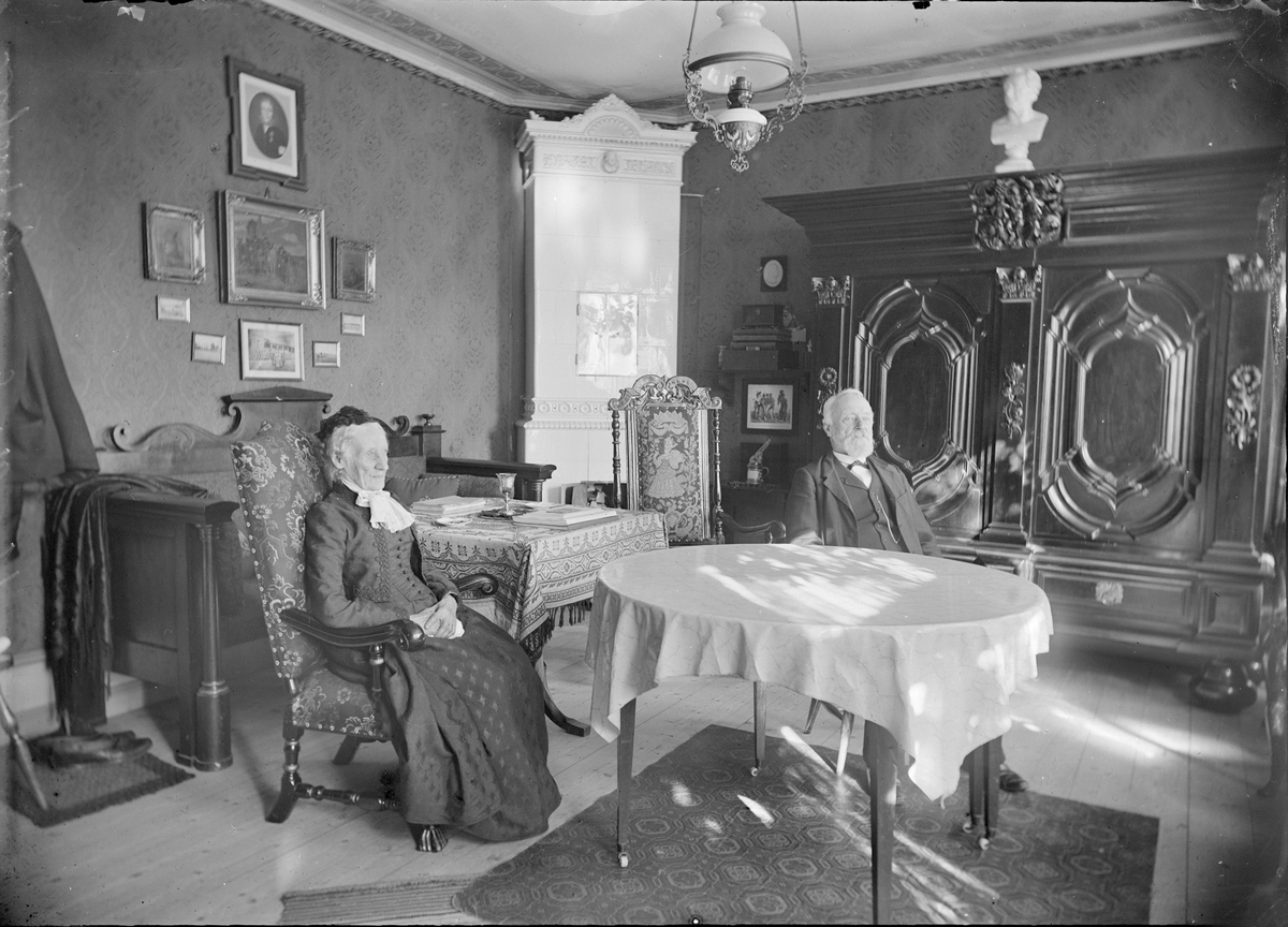 Henri Osti's Fotografiateliér, Kapten J G Leijonflycht i sin bostad med åldrig kvinna, S:t Persgatan 26, Uppsala 1899