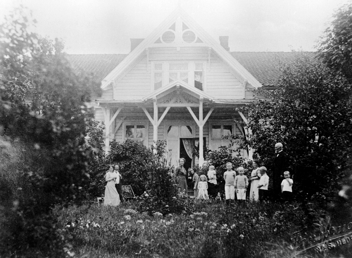 Anno Domkirkeodden, Bestyrerboligen på Toftes Gave, Nedre Sund, Helgøya. Foran huset er Nils Navelsaker med barn og barnebarn. Fra venstre er Eva, Ivar Heggenhaugen, Anna, Ole, Inga, Einar med datteren Sigrid, Astrid Heggenhaugen, Jon Heggenhaugen, Trygve Heggenhaugen, Dagny, Olaf Tandberg, Nils Navelsaker, Hans Hegge…