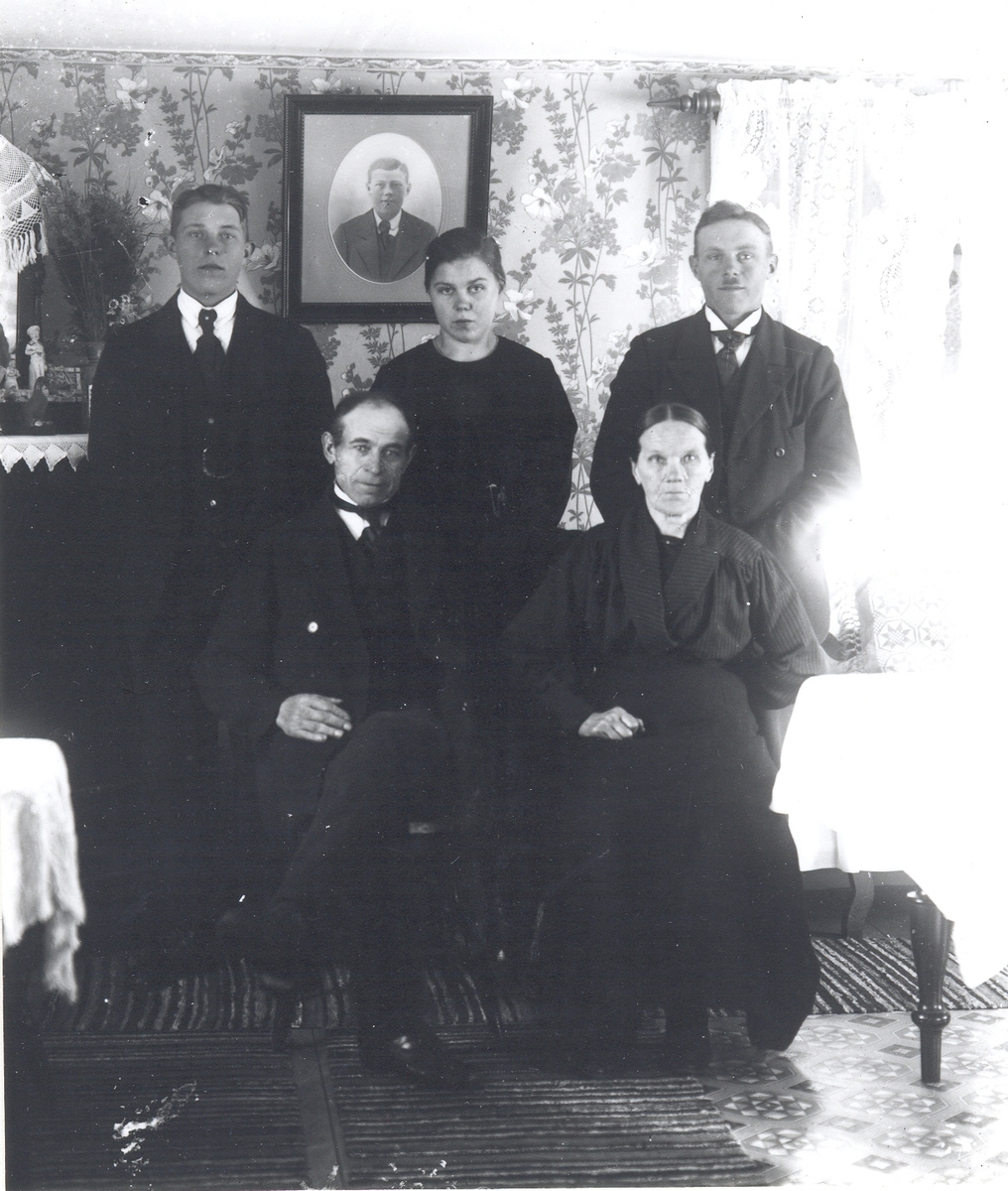 Emil Karlsson, Sittande fr.v.: Johan-Petter Sander och Karolina Sander. Stående fr.v.: Gustav Sander, Anny Sander-Svensson och Ivar Sander. Fotografiet på väggen: John Sander.