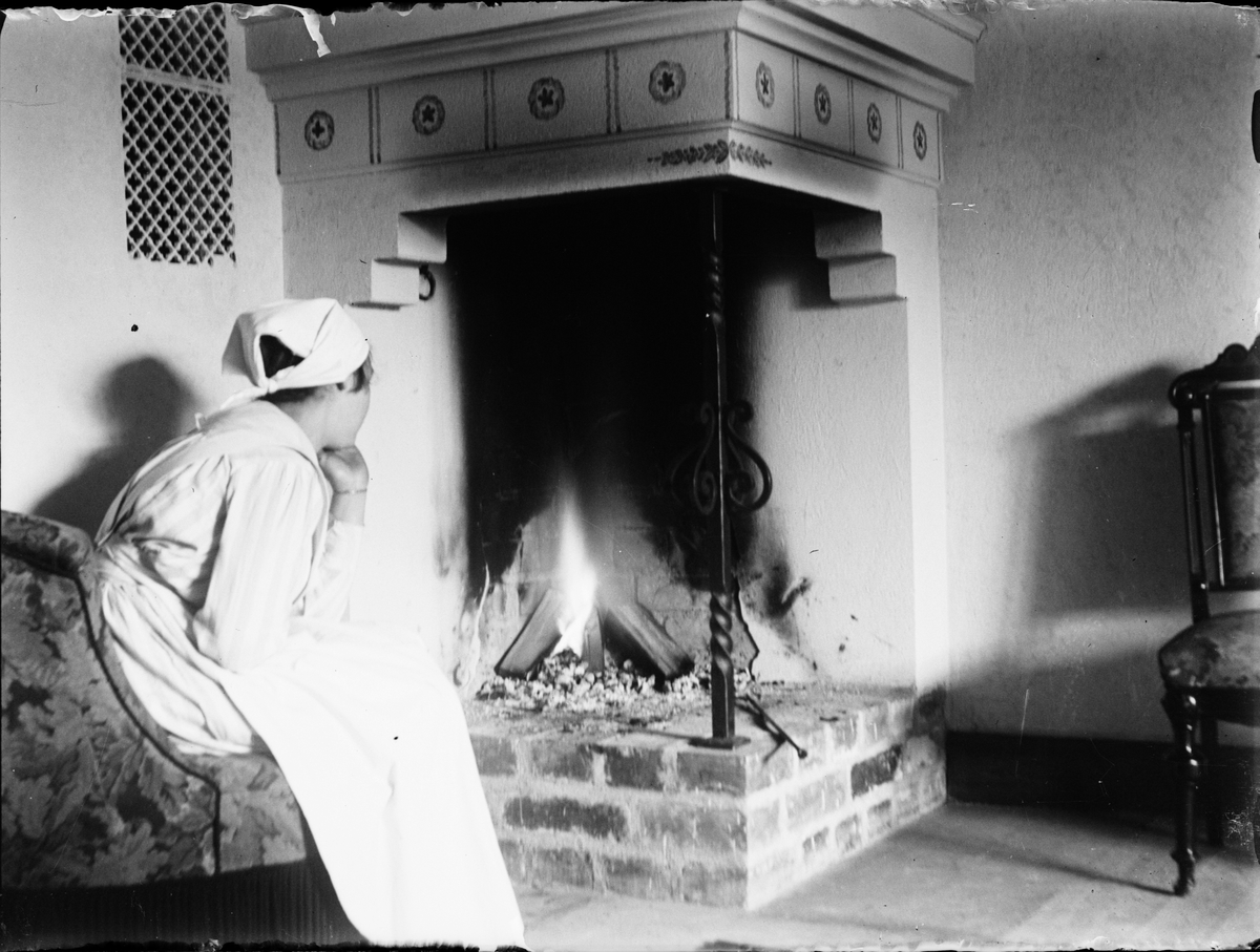 Skötsner-Edhlund, Kvinna sitter vid öppen spis, Östhammar, Uppland