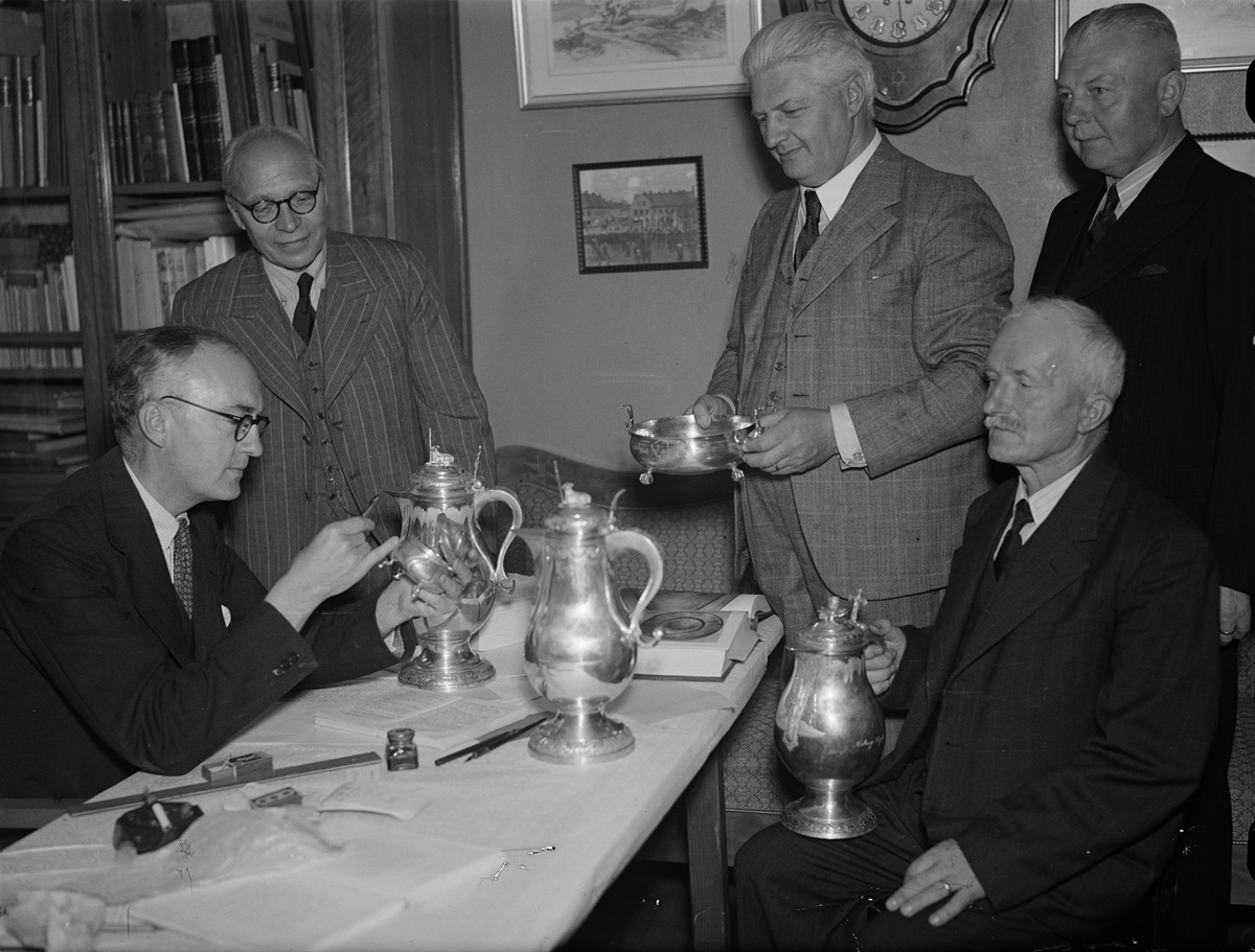 Paul Sandberg, Intendent Nils Aalenius at Upplandsmuseet surveys silver objects, in connection with silver exhibition at Uppsala Fabriks- och hanskInt, Nedre SlottsInt, Uppsala 1944