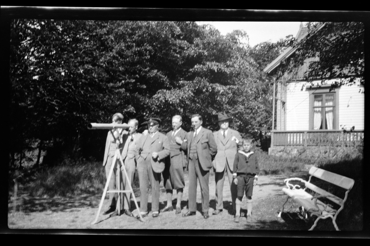 Rolf Sr. Sundt, Seks menn og en gutt ved en kikkert plassert i hagen til familien Sundts sommerhuset på Farøy, Farsund. Fra venstre Bjarne, Peter, Halfdan og Finn Sundt, Johan Buratti, Trygve Sundt og Bjørn Reymert. Fotografert mai 1928.
