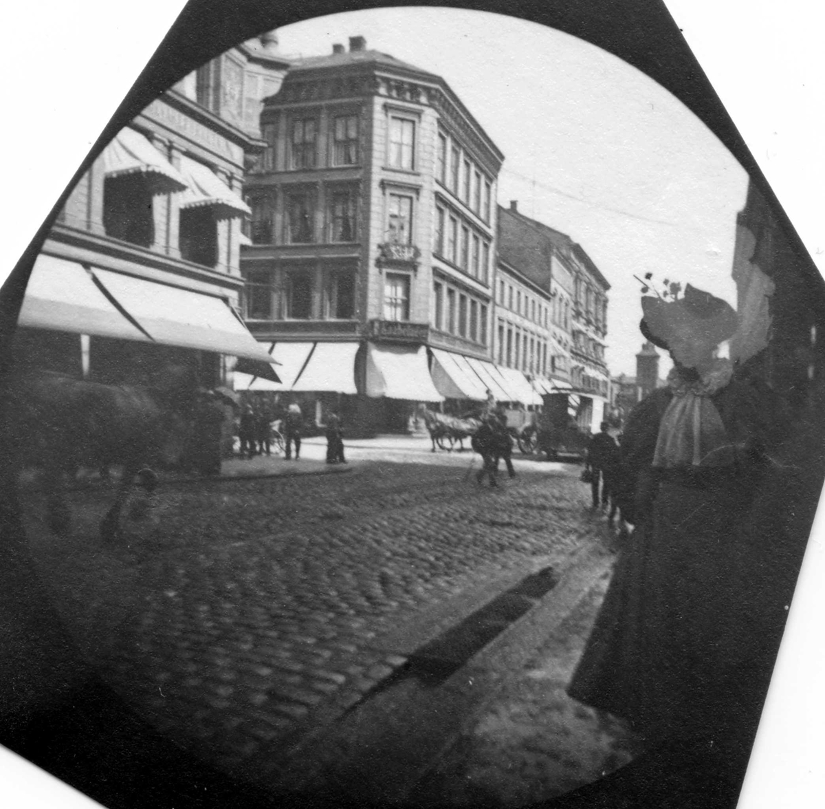 Fredrik Carl Mülertz Størmer, Frk. Lilly Heiberg ant. på Karl Johans gate, Oslo. Butikker med markiser.