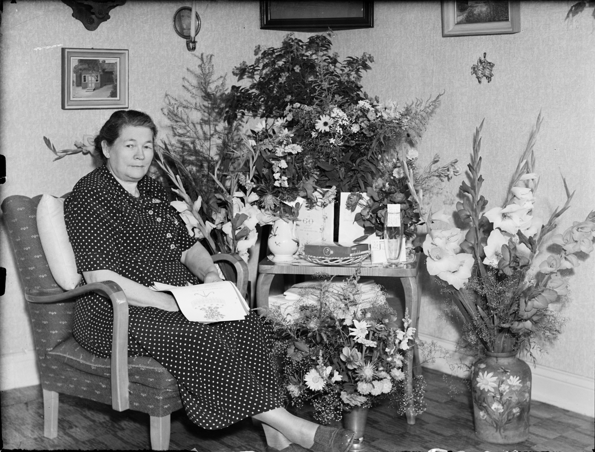 Skötsner-Edhlund, Kvinna i hemmiljö omgiven av blommor, Östhammar, Uppland,