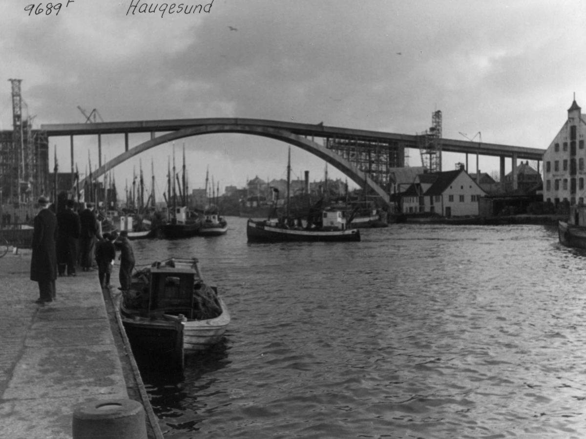 Anders Beer Wilse, Wilse original. Båter inne ved havnen, med en stor bro tvers over bildet. Mennesker på bryggekanten.