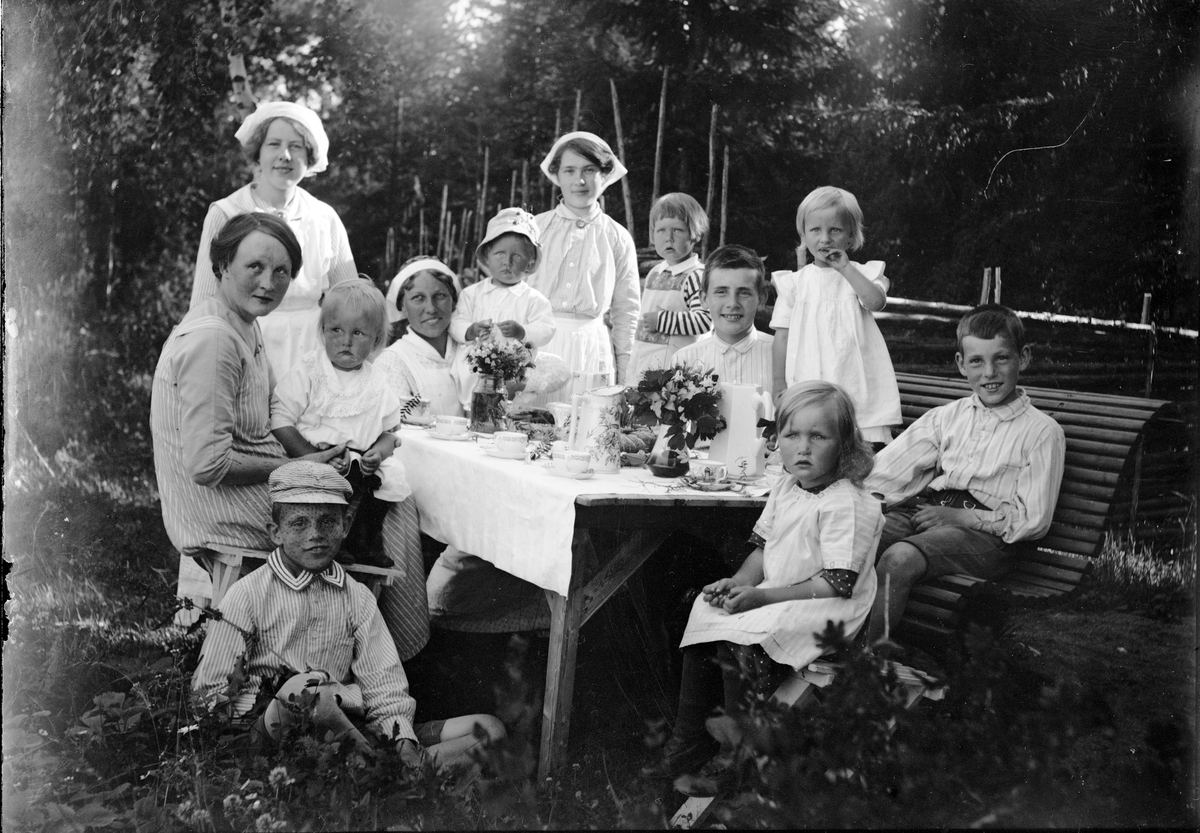 Okänd,, Christiane and Ruben Liljefors children, Marit, Alf, Roland, Ingemar together with other children and household shoes at coffee table outside in garden, likely Sweden