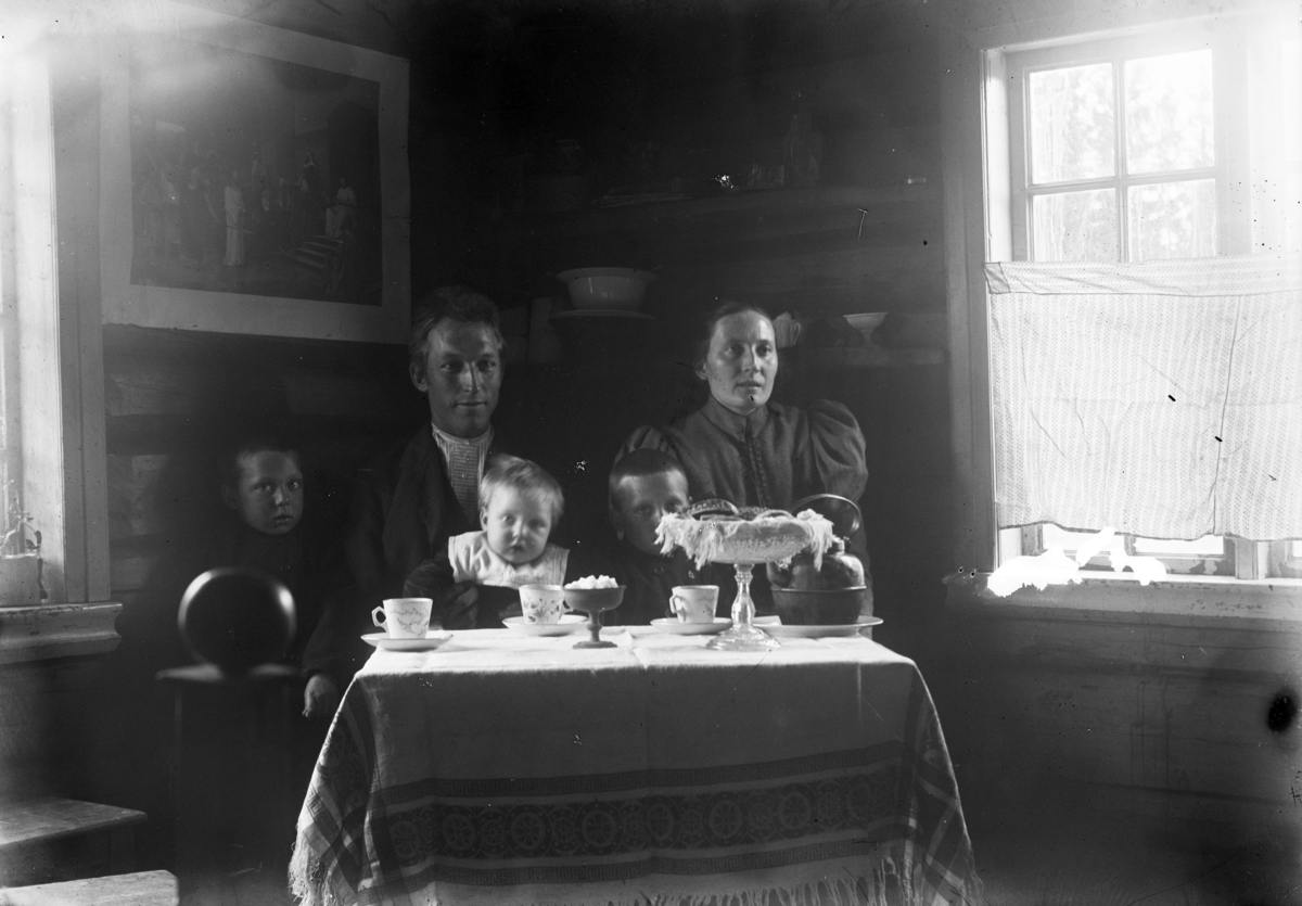 Johannes Larsen Alhaug, Interiør, stue. Ukjent familie ved stuebordet, kaffekjele.