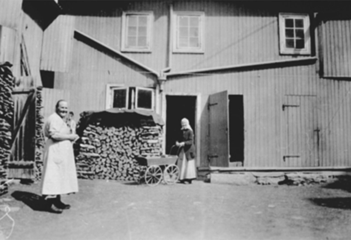Anno Domkirkeodden, 2 DAMER I BAKGÅRDEN TIL KOMPANIGÅRDEN, Companigården i Håkonsgate 45 i Hamar. TIL HØYRE ELISABETH ERIKSEN SOM VAR BAKSTEKONE OG SETERBUDEIE VED BARNEVOGNA. Se også 0401-00639.