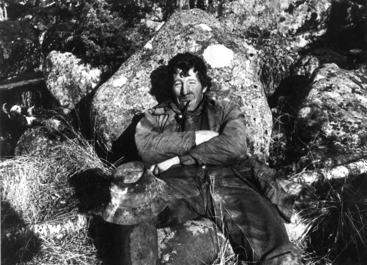 Anna Grostøl, Valle, Aust-Agder 1938. Portrett av Lavrans Homme med pipe som hviler seg ved stampa.
