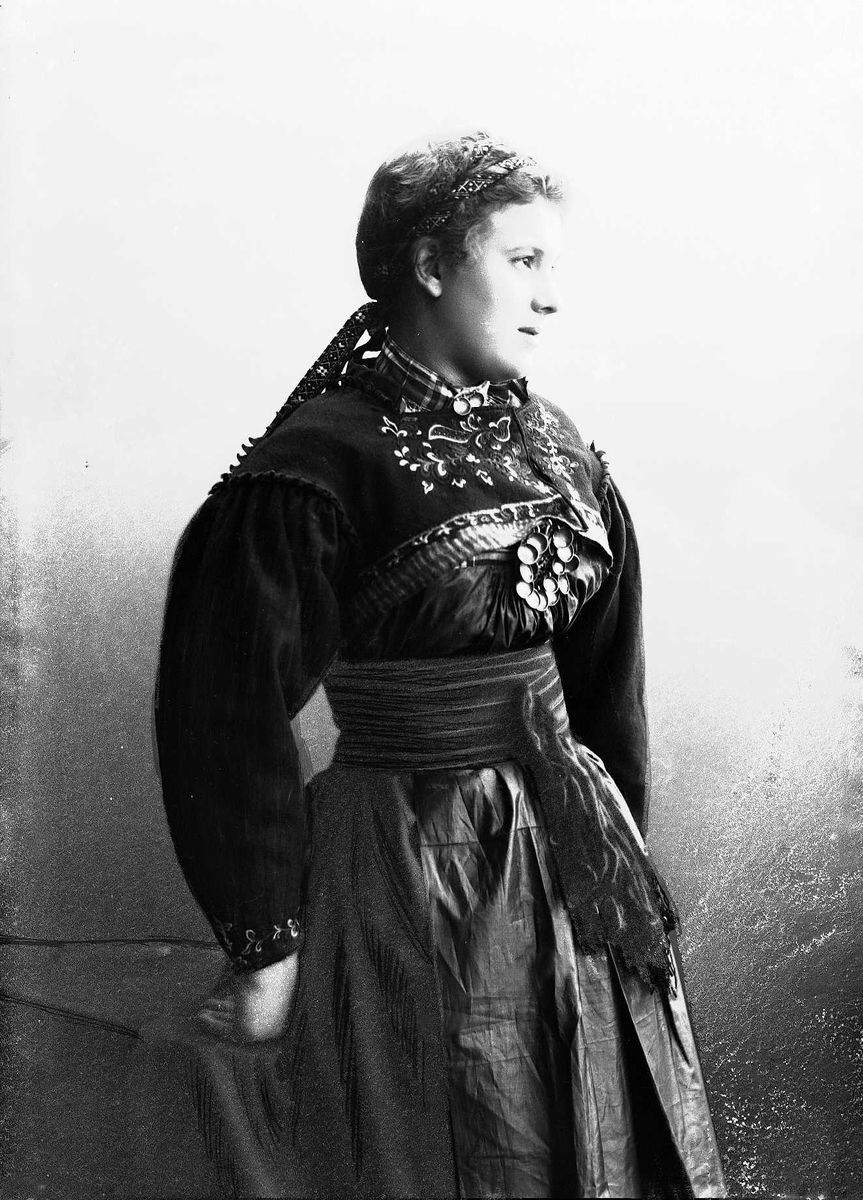 Solveig Lund, Studioportrett av kvinne i drakt og bånd i håret. Avfotografert fra siden.