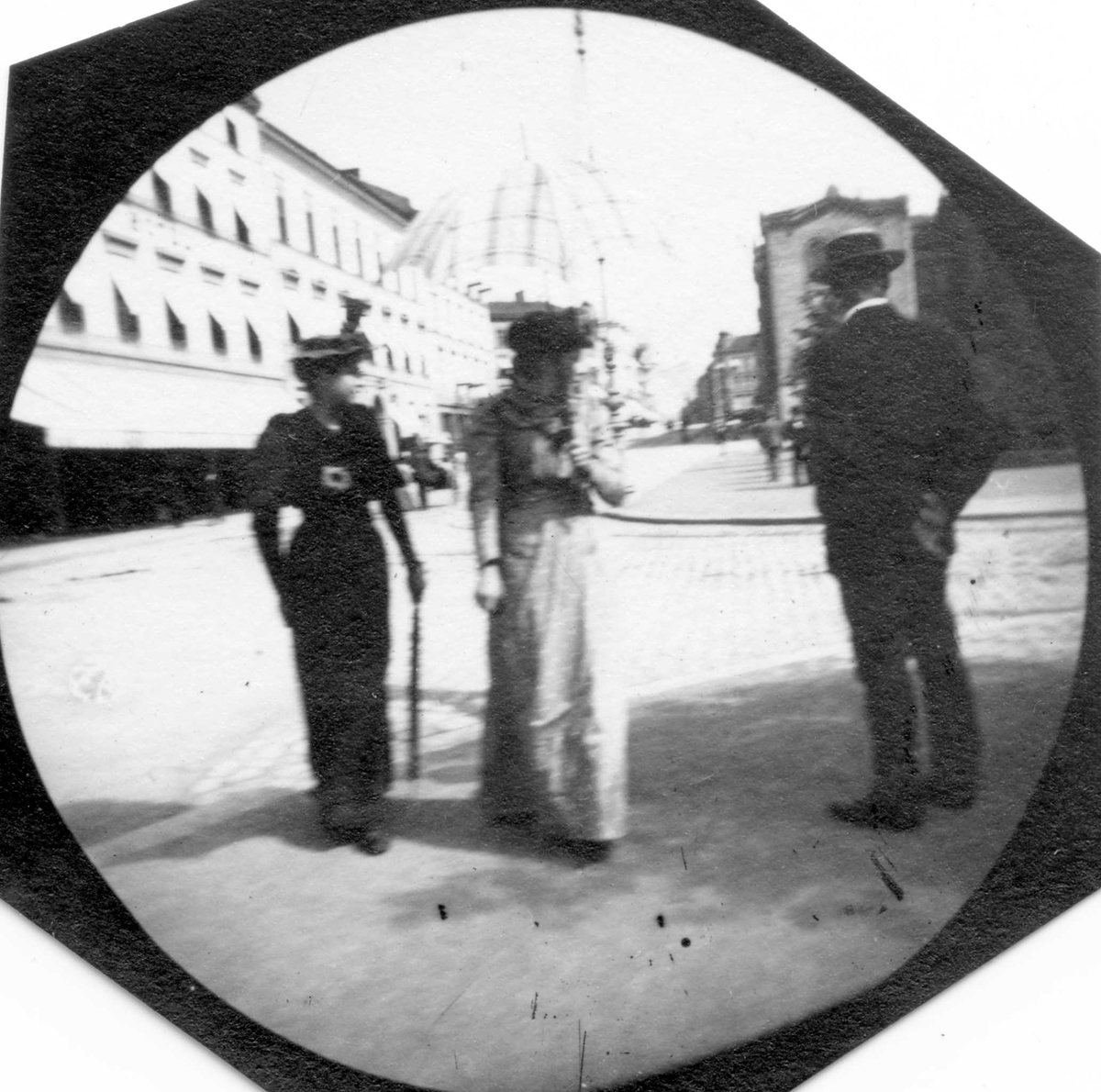 Fredrik Carl Mülertz Størmer, Frk. Augusta Irgens og en annen kvinne spaserer langs Karl Johans gate, Oslo. Stortinget og Grand Hotell i bakgrunnen.