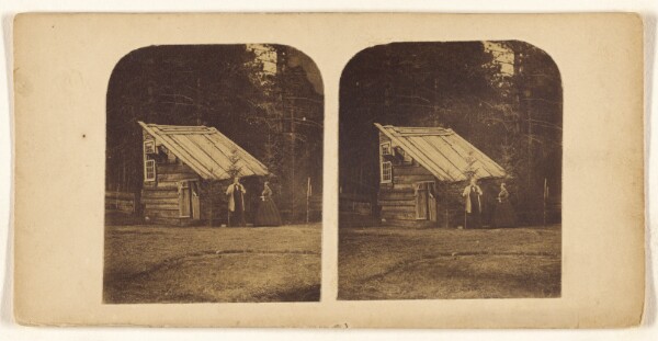 Unknown, [Couple standing before a log cabin]