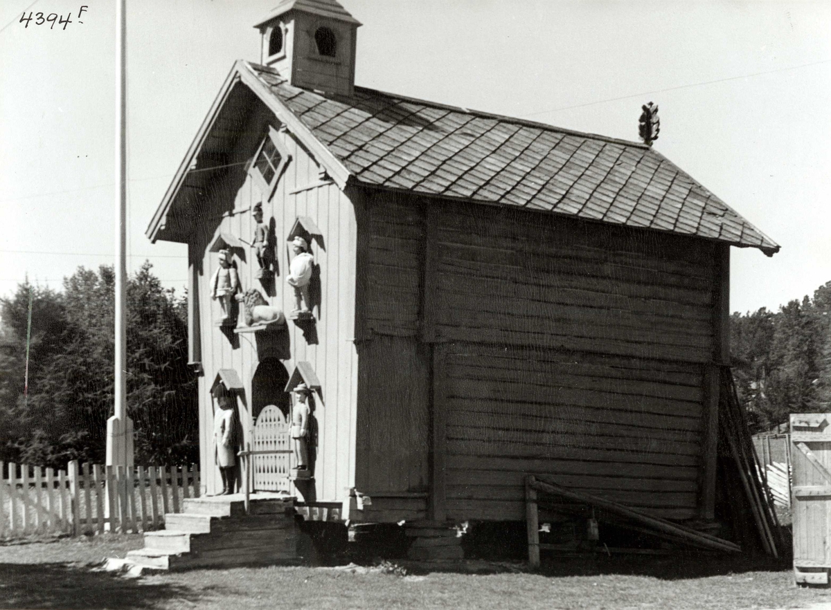 Anders Beer Wilse, Lensmannsgården Østgård, Tolga, Hedmark ant. ca. 1936. Stabbur med figurer på fronten, figurene skal være laget av fanger.