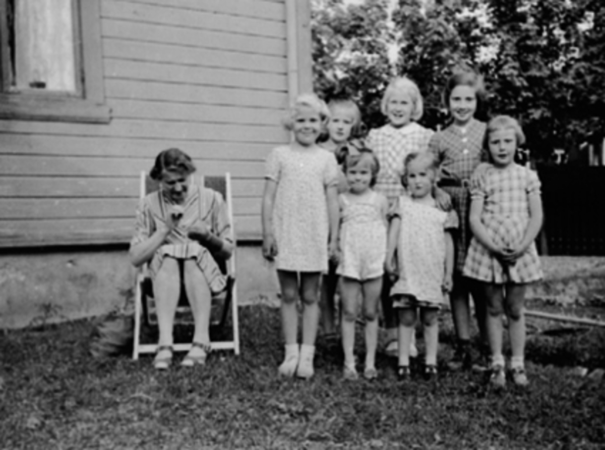 Anno Domkirkeodden, Jenter fra Stangevegen, Hamar. Foran f.v. Berit Gjertsen, Bodil Larsen, Berit Starheim, Randi Knudsen. Bak f.v. Elisabeth Frredriksen, Erna Gjertsen, Eva Kristiansen. Fru Fredriksen sitter i fluktstol og stopper strømper. Bildet er tatt i Briskebyvegen 2.