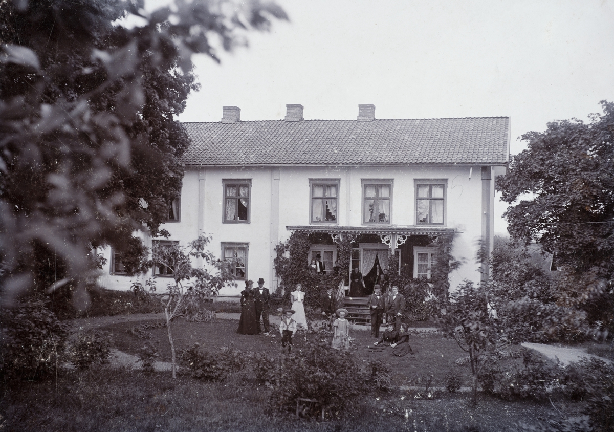 Anno Domkirkeodden, Dæli gård, Veldre, rappet hus med veranda i sveitserstil. Gruppe personer foran hovedbygningen.