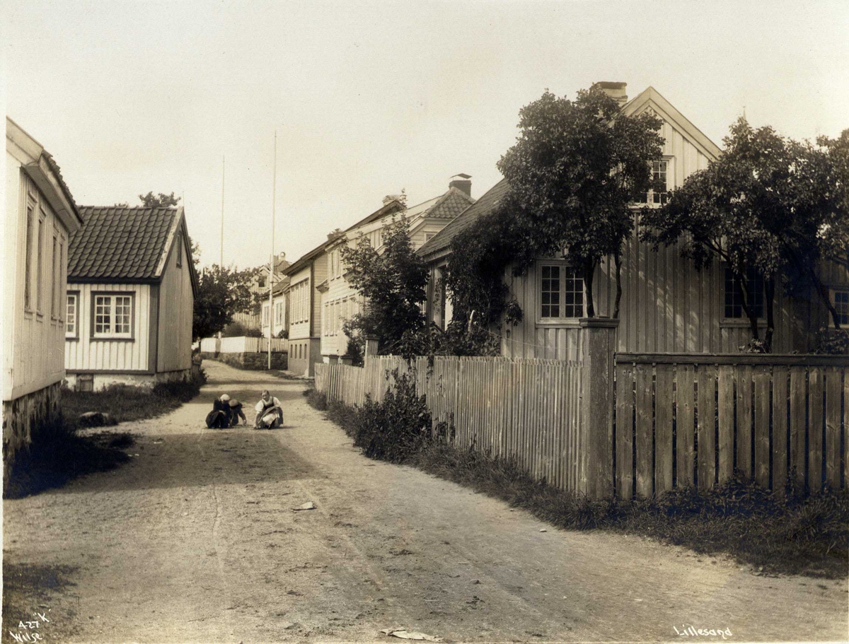 Anders Beer Wilse, Gateparti med trehusbebyggelse, Lillesand, Aust-Agder. Barn leker i gaten.