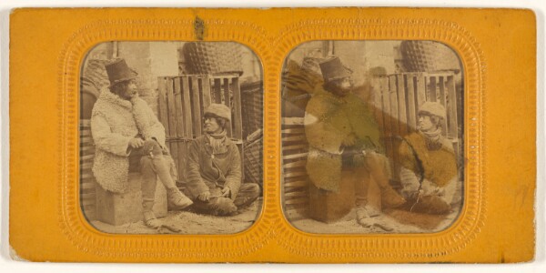 Unknown, [Man in tall hat and sheepskin coat with another man in cap seated up against a crate]