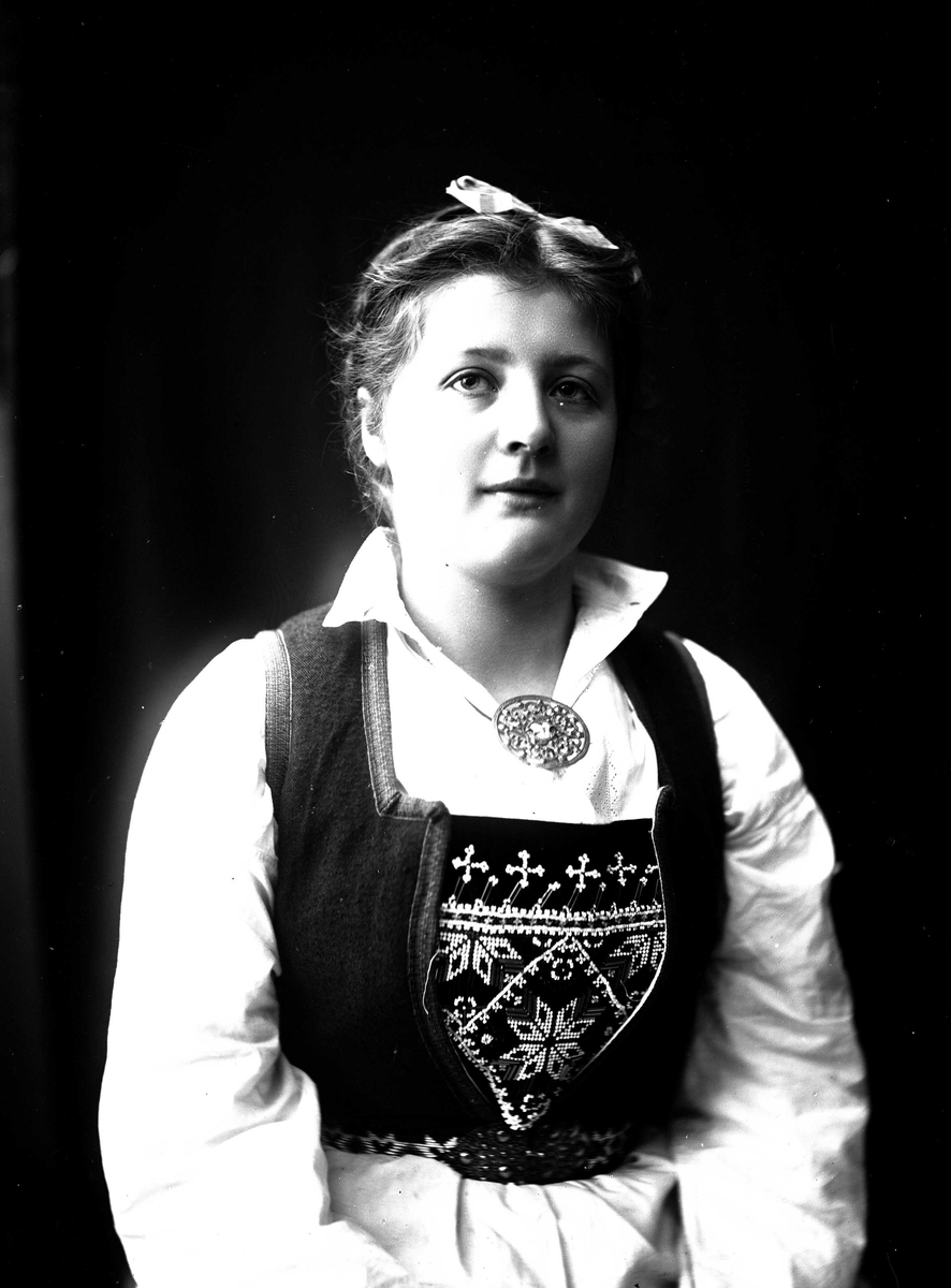 Solveig Lund, Studioportrett av kvinne i drakt med oppsatt hår og sløyfe.