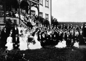 Anno Domkirkeodden, Stor gruppe bryllupsgjester og brudepar på storgård. Nummer tre i første rad fra høyre er Reinert Svendsen.