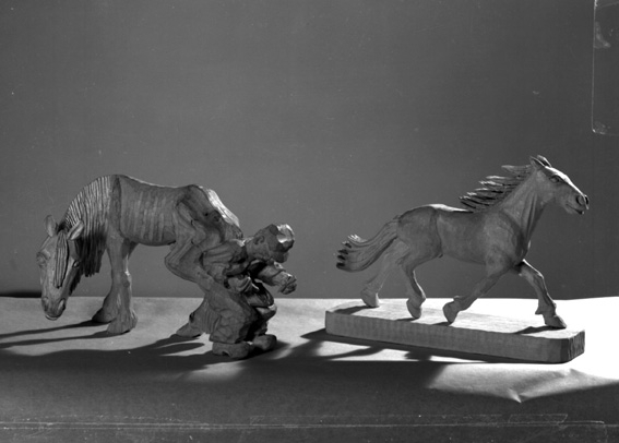 Dan Gunner, Snidade figurer; smed med hästar. Enligt Döderhultarmuseet, Kulturhuset, Oskarshamn, är dessa skulpturer förfalskade Döderhultarmotiv. Man har här försökt efterlikna "ottenbyare" och "springande häst " eller "fullblod". Fotografens ant: Herr Fisk, Skattkärr.