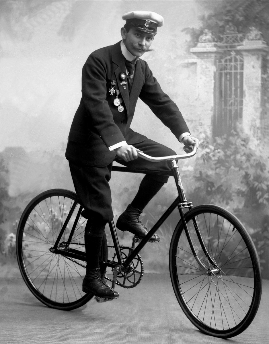 Gustav Borgen, Portrett, mann med uniformslue, medaljer og sykkel.