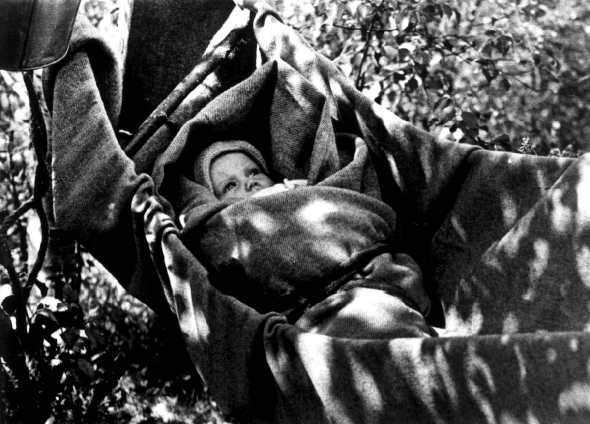 Anna Grostøl, Barn i "ronse", hengekøye, lagd av bæretau og sengeteppe. Fjotland, Kvinesdal, Vest-Agder 1941.