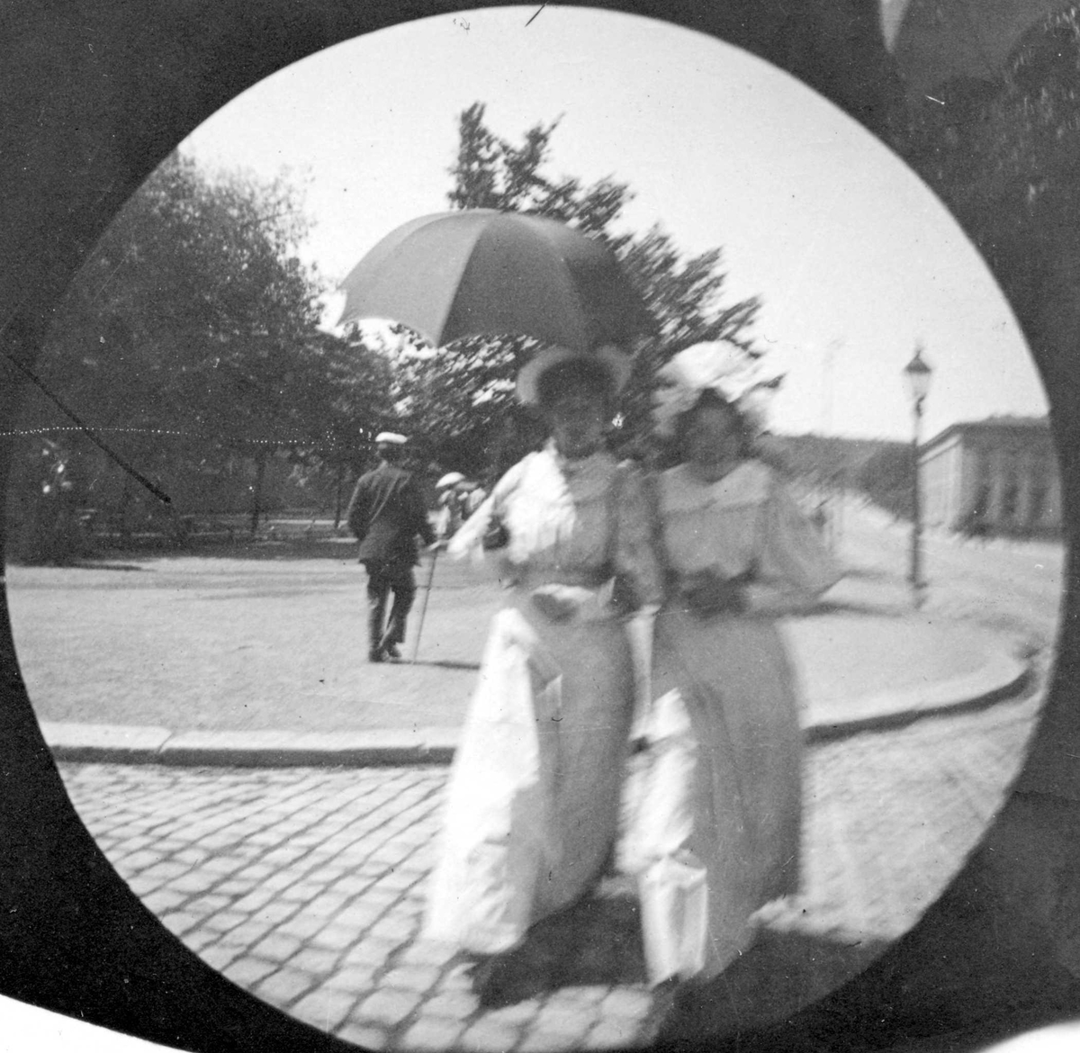 Fredrik Carl Mülertz Størmer, To lyskledde damer spaserer langs Karl Johans gate, Oslo. Universitetet i bakgrunnen.