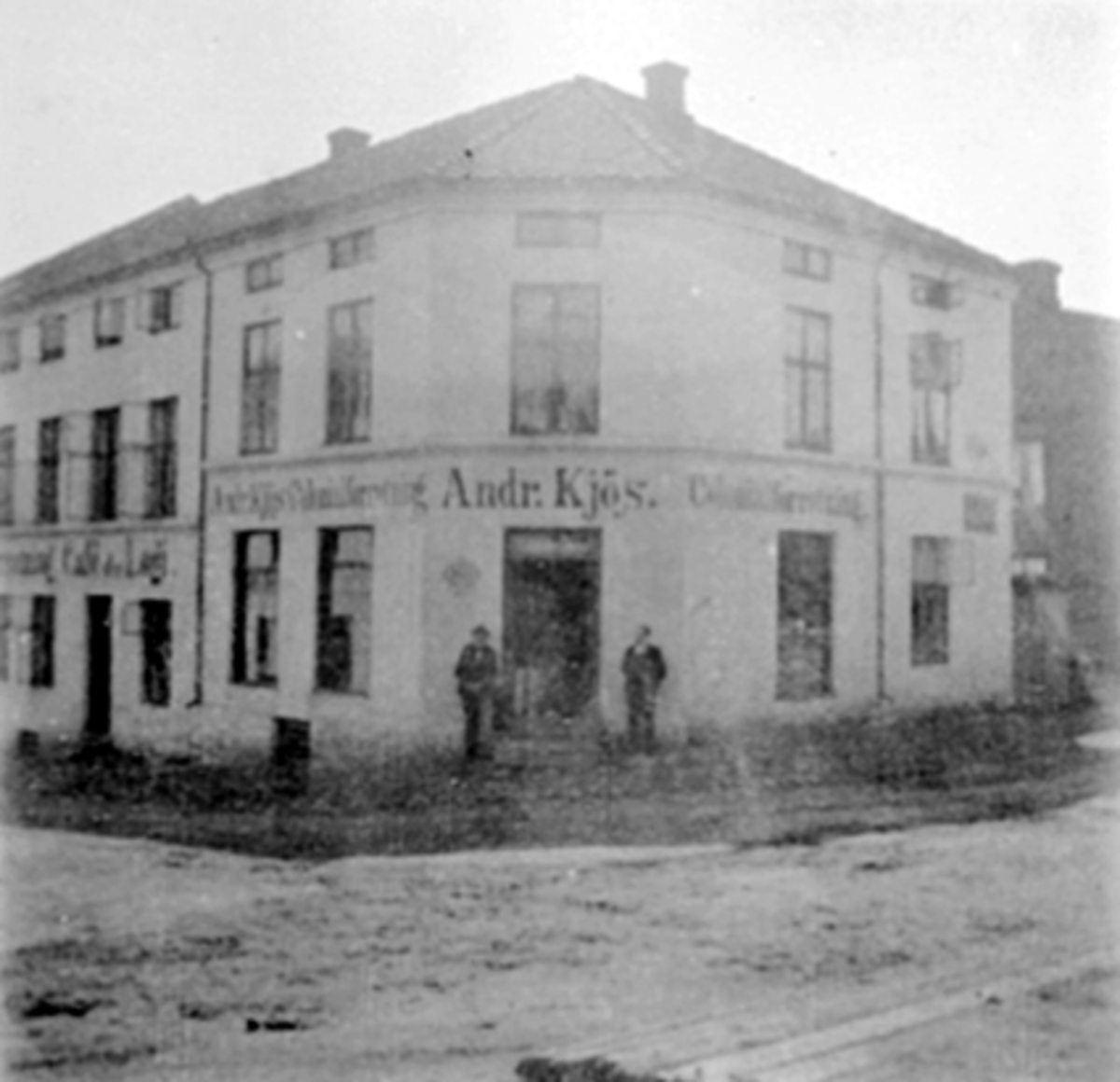 Anno Domkirkeodden, EKSTERIØR, ANDREAS KJØS FORRETNING (BORGER LARSENS GÅRD), 2 MENNAndreas Kjøs åpnet forretning på hjørnet Grønnegt. /Bekkegt. I 1904 flyttet forretningen til enkefru Knudsens gård i Torggt. Broren Kristian Kjøs ble medeier i forretningen i 1904. Se Hamar og Omegns Næringsliv fra 1908 side 16 del 2.