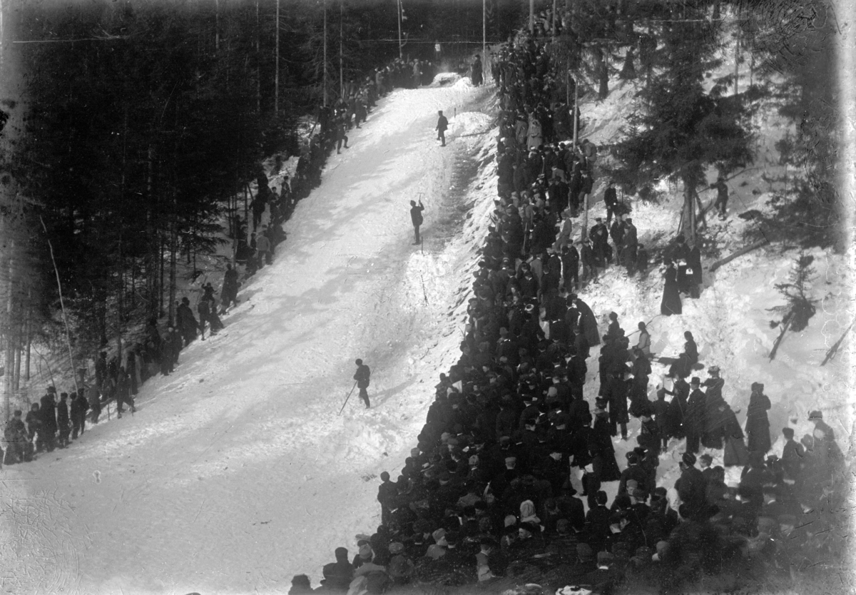 Johannes Larsen Alhaug, Hopprenn. Publikum ser på en skihopper i Hamarbakken.