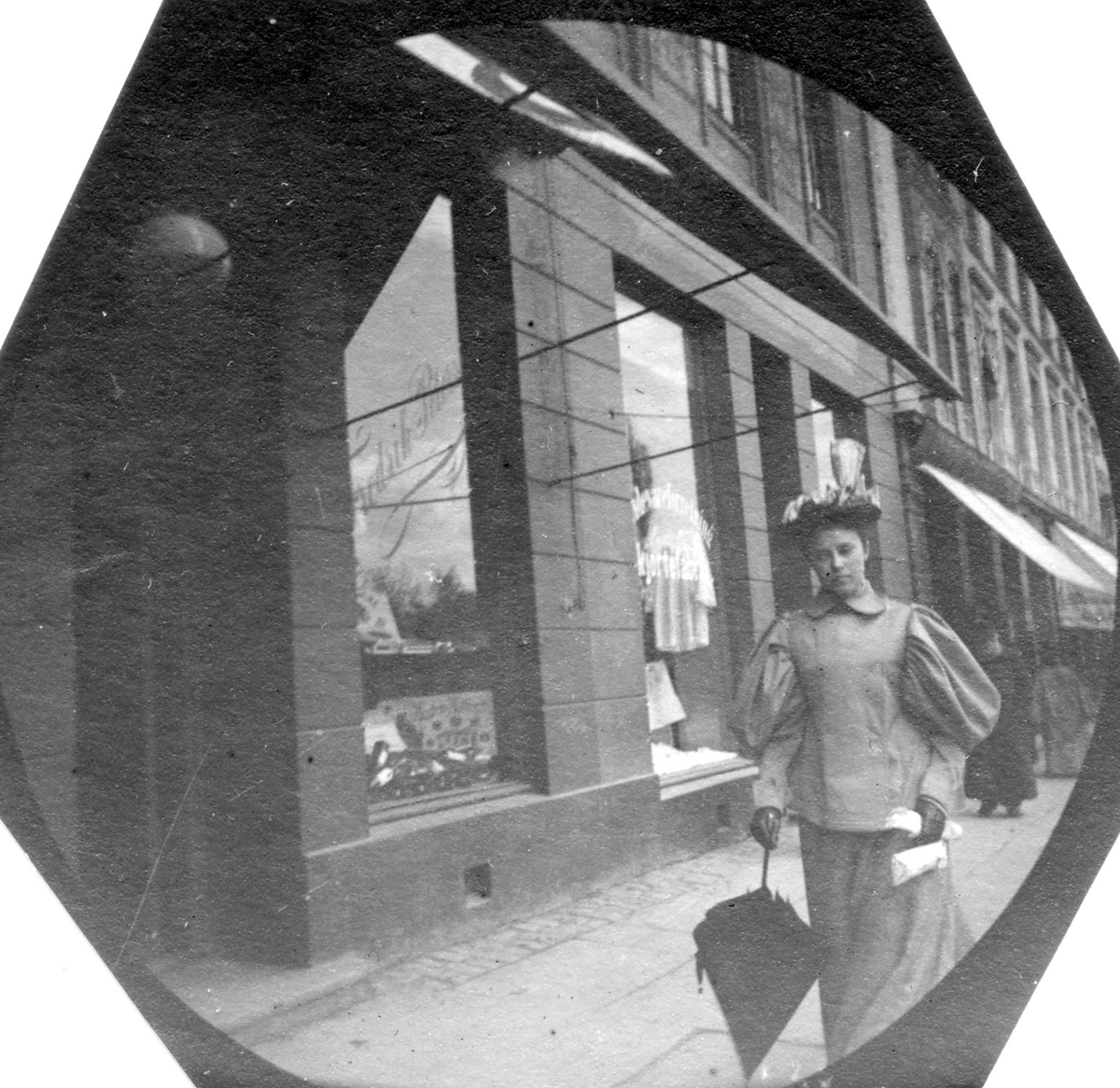 Fredrik Carl Mülertz Størmer, Frk. Bergliot Larsen spaserer langs fortau forbi butikk med markiser, ant. Oslo.