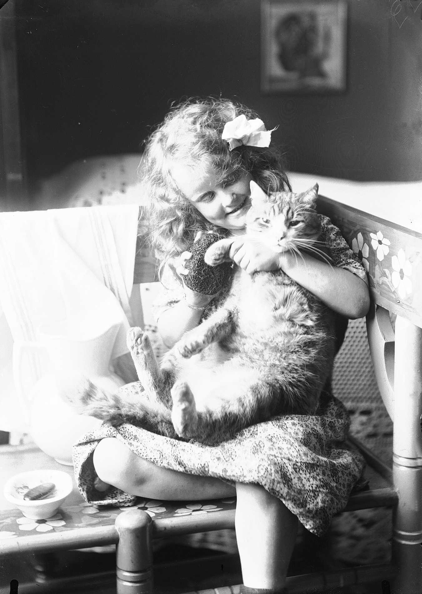 Solveig Lund, Pike sitter på benk med katt på fanget. seng i bakgrunnen.