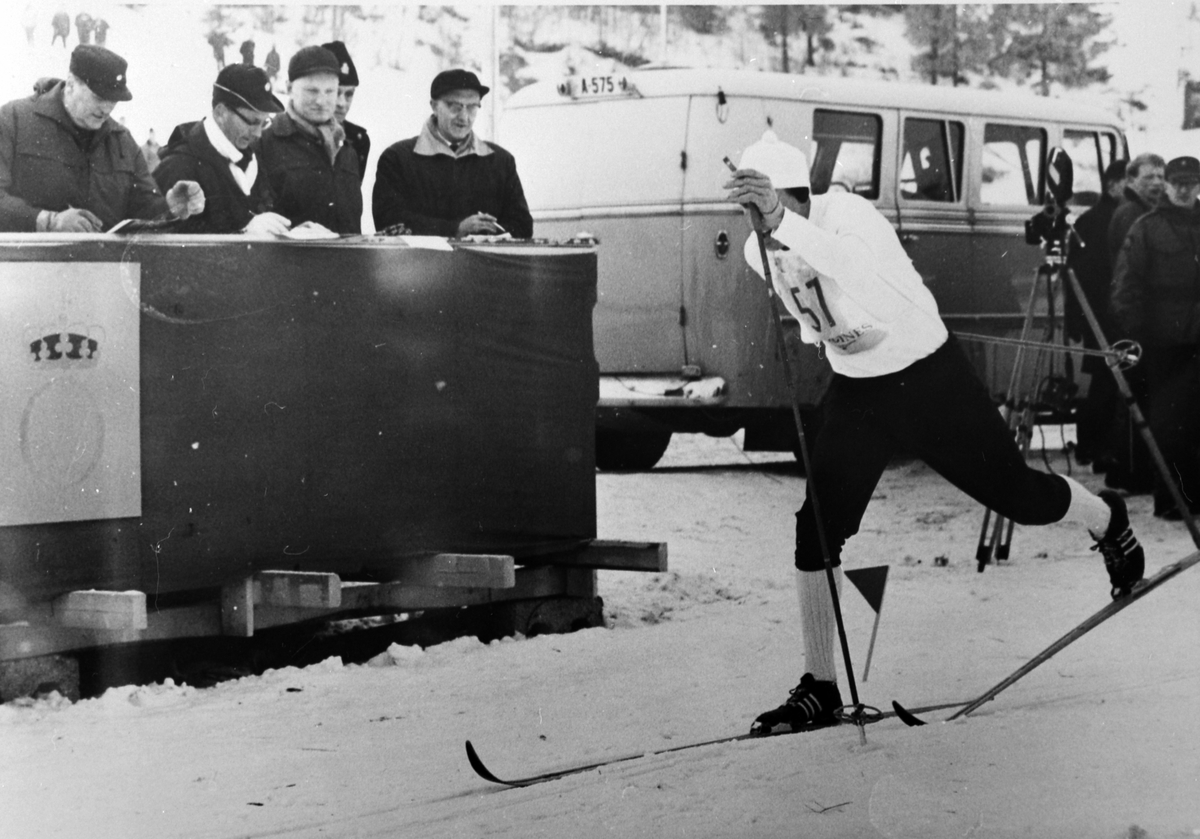 Anno Domkirkeodden, Ole Ellefsæter passerer kongetribuna, NM på ski, 21-23 februar 1964, til venstre er kong Olav, til høyre er ordfører Peder Esbjørnsen, Alu østre, Furnes.