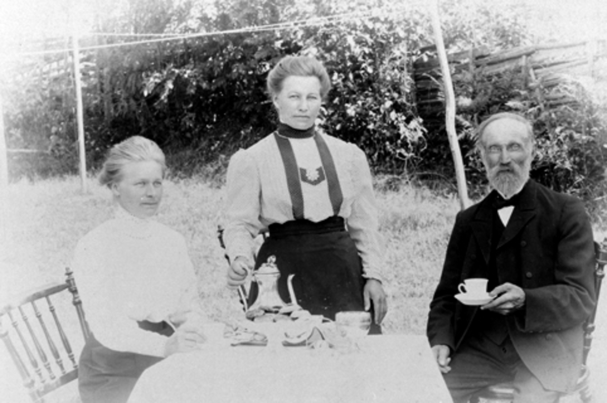 Anno Domkirkeodden, 3 voksne rundt kaffebord utendørs. Fra venstre er Klara Dæhlie, Johanne Dæhlie, Gudbrand Olsen, Høiby, Nes, Hedmark.
