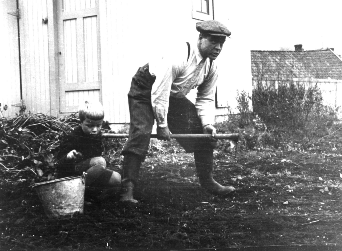 Anna Grostøl, Skjåk, Oppland 1941. Mann og gutt ibber med jorda utenfor boligen.